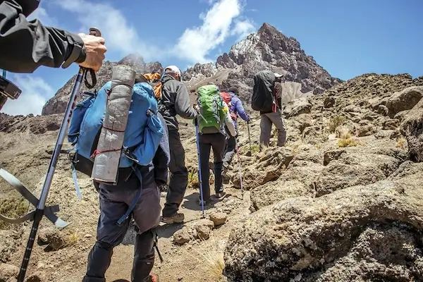 climbers walking up a dusty Kilimanjaro trail